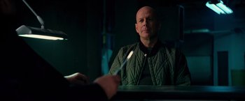 Movie still from “RED” (2010), directed by Robert Schwentke – A man sitting in front of a person holding a spoon; Medium shot, Over the shoulder angle