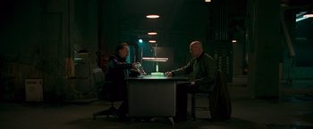 Movie still from “RED” (2010), directed by Robert Schwentke – Two men sitting at a table in a dark room; Wide shot, Low angle