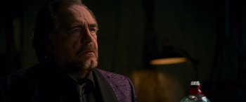 Movie still from “RED” (2010), directed by Robert Schwentke – An older man in a black shirt and a purple jacket; Close Up shot, Low angle