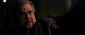 Movie still from “RED” (2010), directed by Robert Schwentke – An older man in a black shirt and a purple jacket; Close Up shot, Low angle
