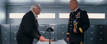 Movie still from “RED” (2010), directed by Robert Schwentke – Two men in uniform shaking hands in a room; Medium shot, Over the shoulder angle