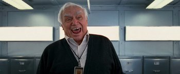 Movie still from “RED” (2010), directed by Robert Schwentke – An older man wearing a black sweater and a white shirt; Close Up shot, Low angle