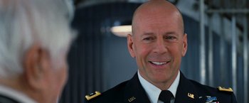 Movie still from “RED” (2010), directed by Robert Schwentke – A man in a military uniform smiling for the camera; Close Up shot, Low angle