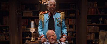 Movie still from “RED” (2010), directed by Robert Schwentke – A man sitting in a chair next to an older man; Medium shot, Low angle
