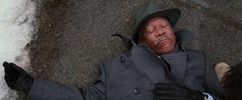 Movie still from “RED” (2010), directed by Robert Schwentke – An older man in a hat and coat sleeping on the ground; Close Up shot, Overhead angle