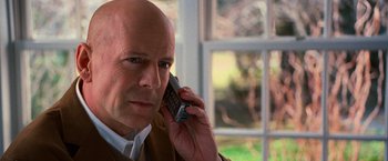 Movie still from “RED” (2010), directed by Robert Schwentke – A bald man talking on a cell phone in front of a window; Close Up shot, Over the shoulder angle