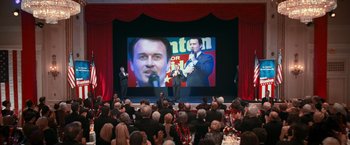 Movie still from “RED” (2010), directed by Robert Schwentke – A crowd of people are watching a man on a stage; Wide shot, High angle