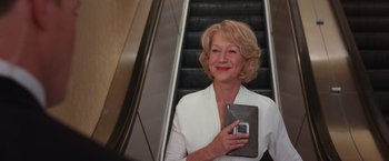 Movie still from “RED” (2010), directed by Robert Schwentke – A woman holding a cell phone standing in front of an escalator; Medium shot, Low angle