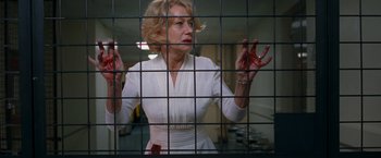 Movie still from “RED” (2010), directed by Robert Schwentke – A woman in a white dress standing behind a metal fence; Medium shot, Low angle