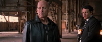 Movie still from “RED” (2010), directed by Robert Schwentke – A bald man in a leather jacket looking to his left; Close Up shot, Low angle