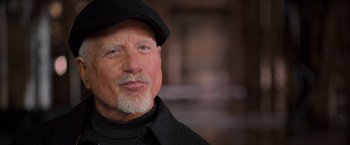 Movie still from “RED” (2010), directed by Robert Schwentke – An older man wearing a black hat and a black jacket; Close Up shot, Over the shoulder angle