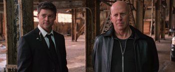 Movie still from “RED” (2010), directed by Robert Schwentke – Two men standing next to each other in an industrial setting; Medium shot, Low angle