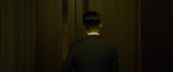 Movie still from “Raging Fire” (2021), directed by Benny Chan – A man in a black suit standing in front of a door; Medium shot, Low angle