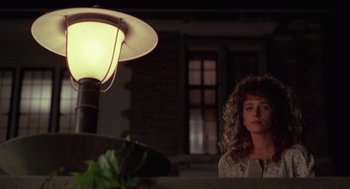 Movie still from “Rain Man” (1988), directed by Barry Levinson – A woman with a furry hood is sitting in front of a lamp; Medium shot, Low angle