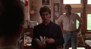 Movie still from “Rain Man” (1988), directed by Barry Levinson – A man in a suit holding a book while standing next to another man; Medium shot, Over the shoulder angle