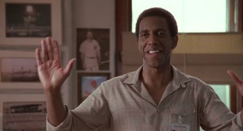 Movie still from “Rain Man” (1988), directed by Barry Levinson – A man smiling and waving at the camera; Medium shot, Low angle
