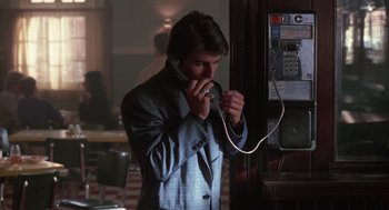 Movie still from “Rain Man” (1988), directed by Barry Levinson – A man in a suit talking on a phone; Medium shot, Over the shoulder angle