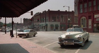 Movie still from “Rain Man” (1988), directed by Barry Levinson – Cars are driving down the street in a city; Extreme Wide shot, High angle