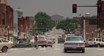 Movie still from “Rain Man” (1988), directed by Barry Levinson – A man standing at a red traffic light on the side of the road; Extreme Wide shot, Over the shoulder angle