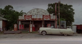 Movie still from “Rain Man” (1988), directed by Barry Levinson – An old car parked in front of an old gas station; Extreme Wide shot, Low angle