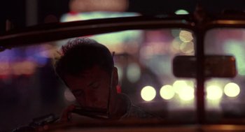 Movie still from “Rain Man” (1988), directed by Barry Levinson – A man looking at his cell phone while sitting in the back of a car; Close Up shot, Over the shoulder angle