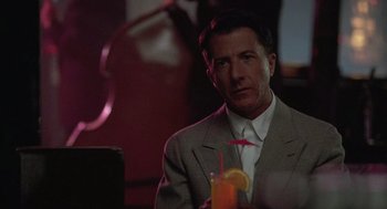 Movie still from “Rain Man” (1988), directed by Barry Levinson – A man sitting at a table holding a drink; Close Up shot, Over the shoulder angle
