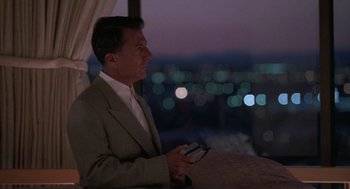 Movie still from “Rain Man” (1988), directed by Barry Levinson – A man in a suit holding a cell phone in his hand; Medium shot, Over the shoulder angle