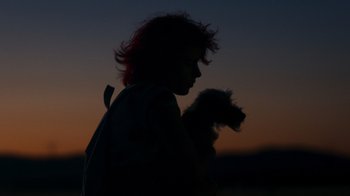 Movie still from “Rainbow” (2022), directed by Paco León – A person with red hair holding a small dog; Wide shot, Low angle