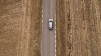 Movie still from “Rainbow” (2022), directed by Paco León – An aerial view of a car driving down a road; Extreme Wide shot, Overhead angle