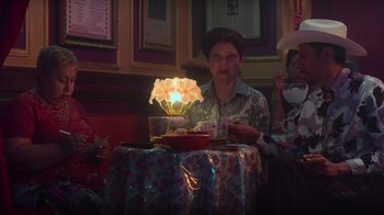 Movie still from “Rainbow” (2022), directed by Paco León – An older woman sitting in front of a lit candle; Medium shot, Over the shoulder angle