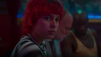 Movie still from “Rainbow” (2022), directed by Paco León – A person with red hair and a green necklace; Close Up shot, Over the shoulder angle