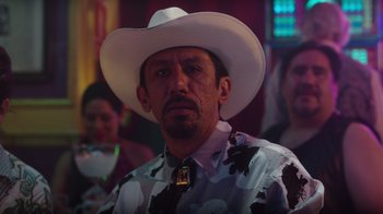 Movie still from “Rainbow” (2022), directed by Paco León – A man wearing a white cowboy hat and a tie; Medium shot, Over the shoulder angle