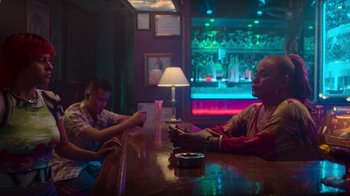 Movie still from “Rainbow” (2022), directed by Paco León – Two men sitting at a table in front of a neon light; Medium shot, Low angle