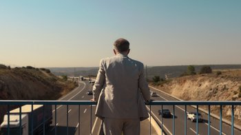 Movie still from “Rainbow” (2022), directed by Paco León – A man standing on a bridge looking over a freeway; Wide shot, High angle