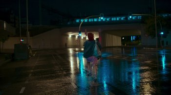 Movie still from “Rainbow” (2022), directed by Paco León – Two people are walking in the rain at night; Wide shot, Low angle