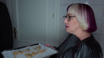 Movie still from “Rainbow” (2022), directed by Paco León – A woman sitting in front of a tray of cookies; Close Up shot, High angle