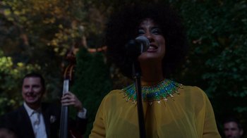 Movie still from “Rainbow” (2022), directed by Paco León – A woman in a yellow shirt is singing into a microphone; Medium shot, Low angle