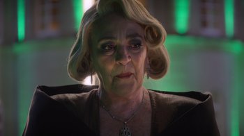 Movie still from “Rainbow” (2022), directed by Paco León – An older woman with blonde hair wearing a necklace; Close Up shot, Over the shoulder angle