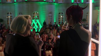 Movie still from “Rainbow” (2022), directed by Paco León – Two women are holding wine glasses in front of an audience; Medium shot, Over the shoulder angle