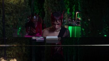 Movie still from “Rainbow” (2022), directed by Paco León – A woman in a black dress sitting at a table; Medium shot, High angle