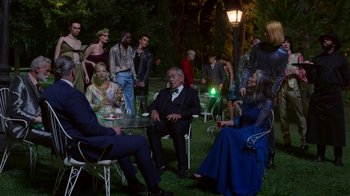 Movie still from “Rainbow” (2022), directed by Paco León – A group of people sitting at a table in the grass; Wide shot, High angle