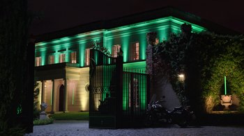 Movie still from “Rainbow” (2022), directed by Paco León – A building lit up at night with green lights; Extreme Wide shot, Low angle