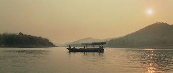 Movie still from “Rambo” (2008), directed by Sylvester Stallone – A boat floating on a body of water near mountains; Extreme Wide shot, High angle