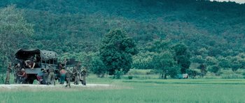 Movie still from “Rambo” (2008), directed by Sylvester Stallone – A man standing next to a truck on a dirt road; Extreme Wide shot, High angle