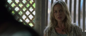 Movie still from “Rambo” (2008), directed by Sylvester Stallone – A woman with long blonde hair sitting in front of a wooden fence; Close Up shot, Over the shoulder angle