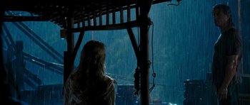 Movie still from “Rambo” (2008), directed by Sylvester Stallone – A woman sitting on a porch in the rain; Wide shot, Over the shoulder angle