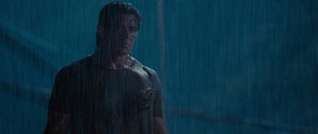 Movie still from “Rambo” (2008), directed by Sylvester Stallone – A man standing in the middle of a rain storm; Medium shot, Low angle