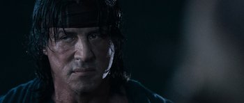 Movie still from “Rambo” (2008), directed by Sylvester Stallone – A man with long black hair; Close Up shot, Low angle