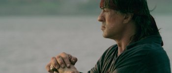 Movie still from “Rambo” (2008), directed by Sylvester Stallone – A person holding something in his hand; Close Up shot, Low angle