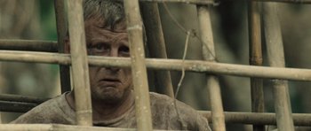 Movie still from “Rambo” (2008), directed by Sylvester Stallone – A man looking through a wooden fence; Close Up shot, Over the shoulder angle